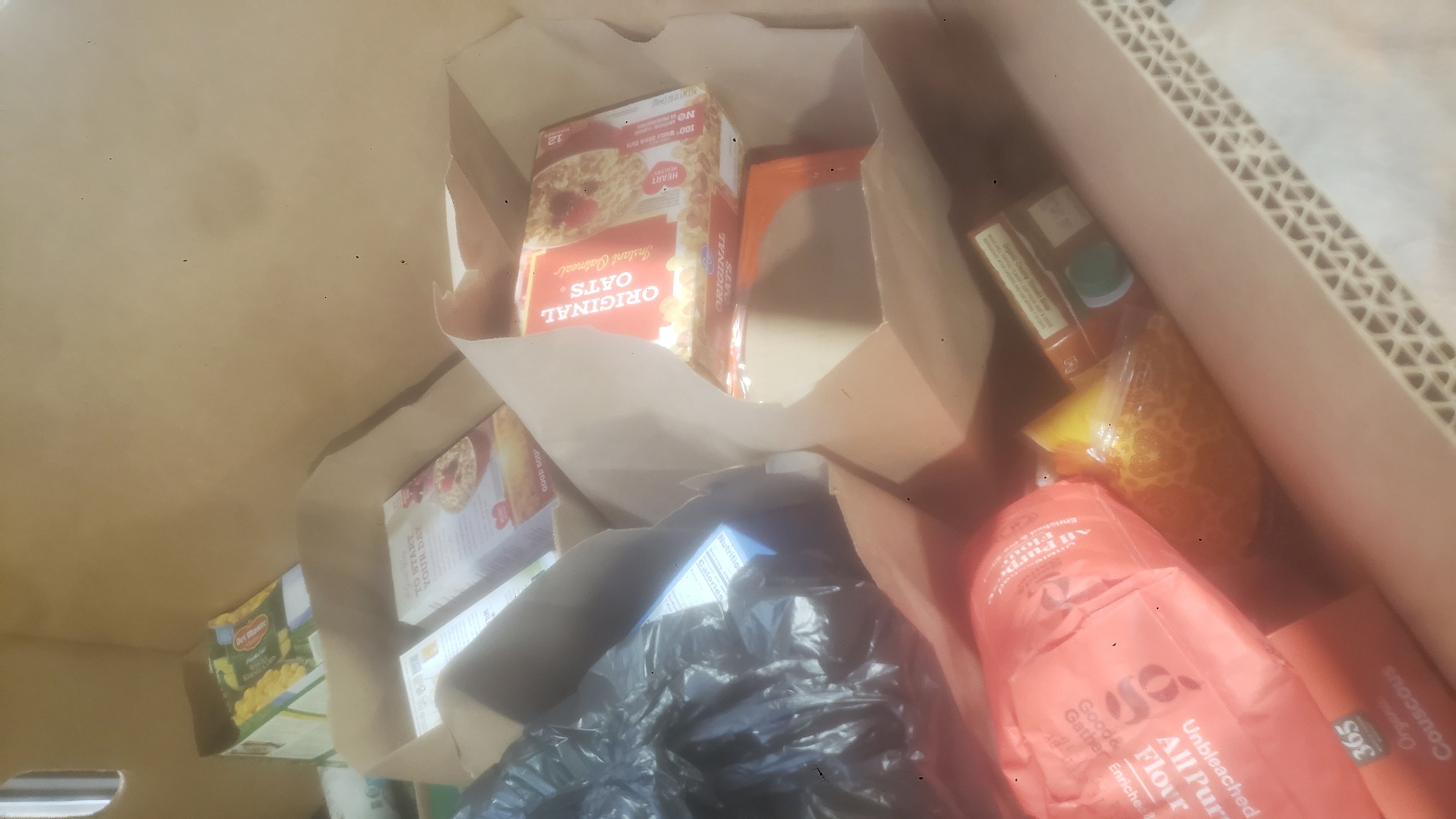 Paper bags filled with food and ingredients in a cardboard container.